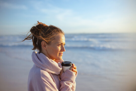 relaxed stylish woman in cosy sweater at beach in evening