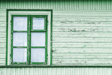 Obraz na płótnie Canvas Rustic window in wooden village cottage house. Green wood wall. Countryside architecture background. Empty copy space peeling paint texture.