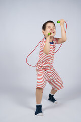 Happy 5 year old boy jumping rope on a white background, a place for text