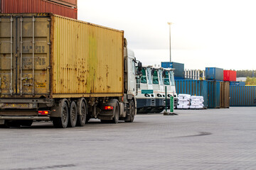 Truck while loading in logistic shipping yard with cargo container. Forklift truck handling truck....