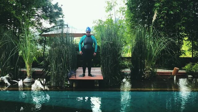 Caucasian action woman jumps vertically into the pool generating splash to get out of crol swimming full length lock down camera