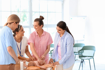 Young pregnant women learning how to put diaper in class