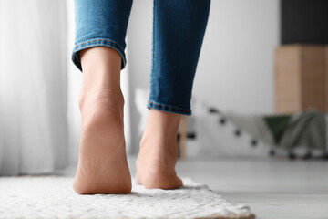 Female bare feet on rug in room, closeup