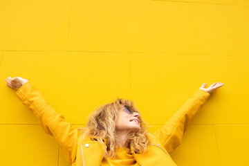 middle aged woman excited from happiness on yellow wall background outdoors