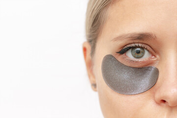 Cropped shot of a young attractive caucasian woman with black gel glittering patches on the skin under her eyes isolated on a white background. Skin care, cosmetology. Beauty concept. Close-up