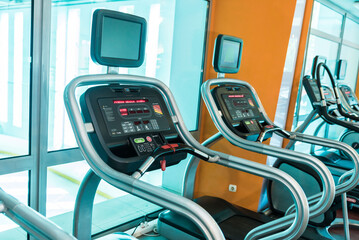 Interior of modern gym fitness room with large windows and treadmills