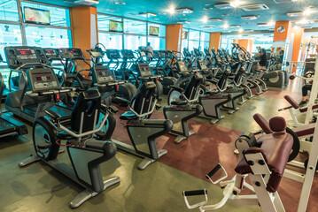 Fototapeta premium Interior of modern gym fitness room with large windows and treadmills