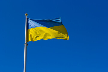 National flag of Ukraine against blue sky, The wind blows out