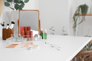 Makeup brushes and cosmetics on table in room