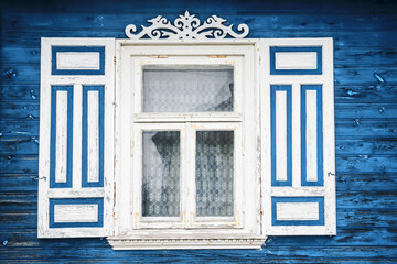 Wooden rustic window in small cottage house. Vintage blue paint wall. Transparent glass window. Decorative white shutter.
