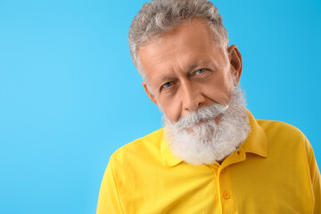 Senior bearded man in yellow shirt on blue background