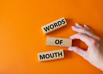 Words of mouth symbol. Concept word Words of mouth on wooden blocks. Businessman hand. Beautiful orange background. Business and Words of mouth concept. Copy space