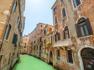 Fototapeta na wymiar Antique Architecture Walls in Venezia with a clear canal water during summer