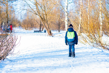 boy, schoolboy with a backpack goes through the park in winter