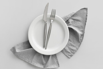 Table setting with cutlery in plate and napkin on grey background