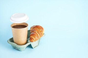 Open paper cup of coffee and tasty croissant on color background
