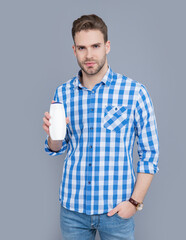 young guy hold bottle of aftershave product. guy hold aftershave product isolated on grey