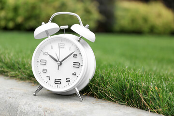 White vintage alarm clock in park, closeup