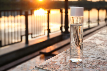 Bottle of water on embankment at sunset, closeup