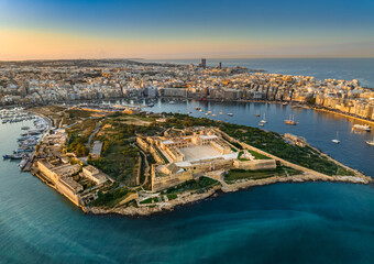 Fototapeta premium Aerial sunset view of Manoel island and fort, Sliema city on background. Gzira city, Malta