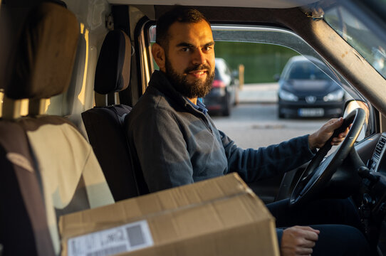 Delivery man working inside a van next to a parcel ready to drive. Looking at camera.