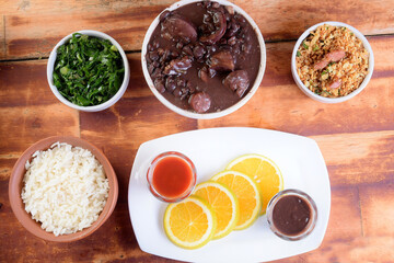 delicious Brazilian feijoada with farofa rice salad served in bowl over piece of wood on blurred background, Brazilian food