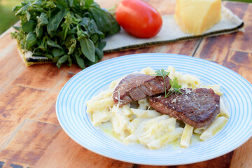 white sauce pasta and beef filet mignon with parmesan cheese, tomato, basil, herbs, delicious food from Italian and French cuisine