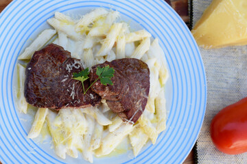 white sauce pasta and beef filet mignon with parmesan cheese, tomato, basil, herbs, delicious food from Italian and French cuisine