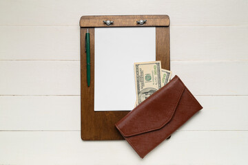 Wallet with money, clipboard and pen on white wooden background. Budget concept