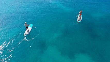 Aerial drone photo of two women practising Stand Up Paddle board or SUP surf in tropical exotic...
