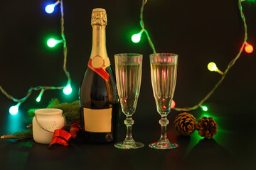 Bottle and glasses of champagne on dark background