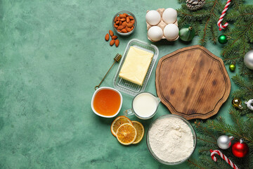 Composition with wooden cutting board, ingredients for Christmas bakery, decorations and fir branches on color background