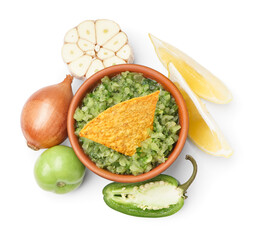 Bowl of green salsa sauce with nacho and ingredients on white background