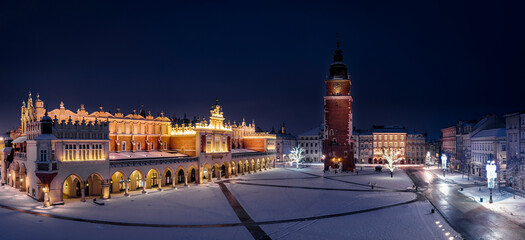 Panorama of Main Square (Saint Mary's Basilica, Sukiennice - Town Hall, Town Hall Tower) in Krakow at night in snowy winter, Poland