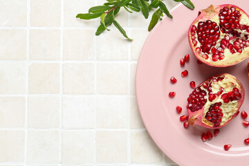 Plate with fresh pomegranates on light tile