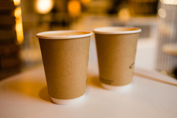 Close up two cardboard coffee cups take away on table over bokeh background copy space and empty space for text - coffee shop and take away drink concept