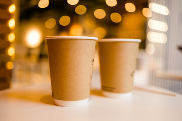 Close up two cardboard coffee cups take away on table over bokeh background copy space and empty space for text - coffee shop and take away drink concept