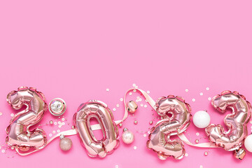 Figure 2023 made of balloons and Christmas decorations on pink background