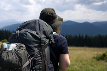 Young girl in a hat is trekking, hiking in the mountains.