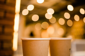 Close up two cardboard coffee cups take away on table over bokeh background - coffee shop and take away drink concept