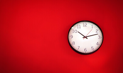 red white wall clock hanging on a wall a simple flat lay image of a plastic wall clock over a red turquiose background with copy space and a central element.                      