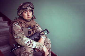 A soldier sits on the stairs with a weapon., machine gun.