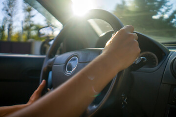 Female hands on the steering wheel, driving a car.