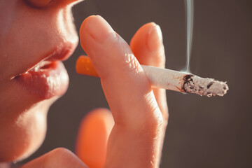 Woman is smoking, holding a cigarette in her hand.