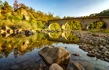 Fototapeta na wymiar peaceful river with water reflection and old stone bridge.
