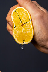 Hand squeezes out a lemon, on which the clock is drawn. Creative hours as a symbol of wasted time,...