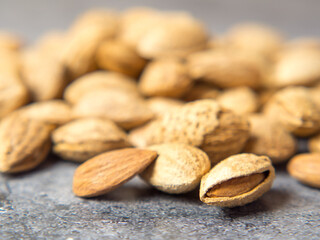 shelled almonds on a dark stone table with a wooden spoon and a bowl. Almonds in a wooden bowl.