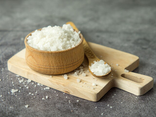 sea crystal salt in a wooden bowl and spoon on a wooden board
