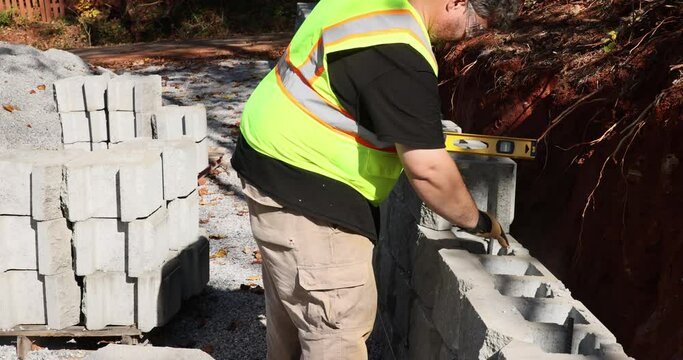 An installation of newly constructed large block retaining wall by contractor in construction site during construction phase