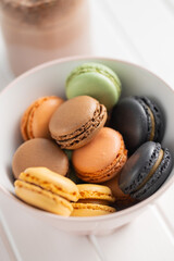 Sweet macaron dessert. Colorful macarons in bowl on white table.